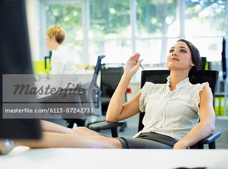 Businesswoman relaxing with feet up on desk in office