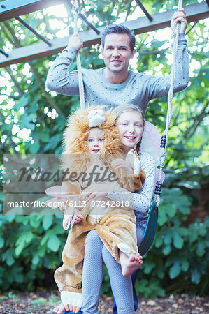 Father and children playing together on swing