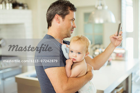 Father using cell phone and holding baby