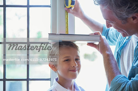 Father measuring son's height on wall