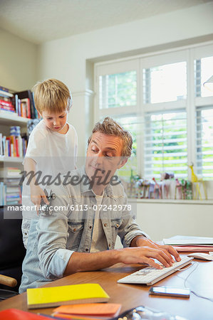 Boy distracting father at work in home office