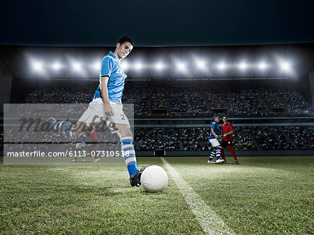 Soccer player kicking ball on field