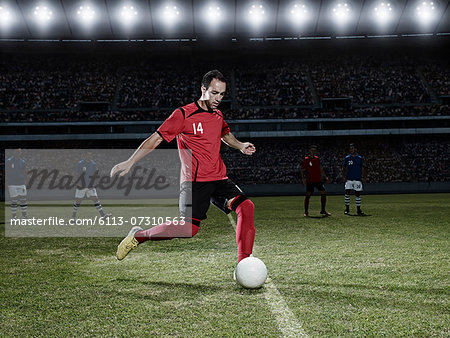 Soccer player kicking ball on field