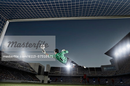 Goalie jumping for ball in soccer net Goalie jumping for ball in soccer net