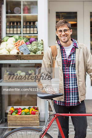 Man with coffee cup and bicycle on city street