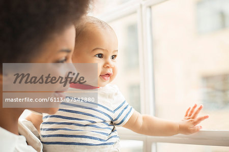 Mother and baby boy looking out window