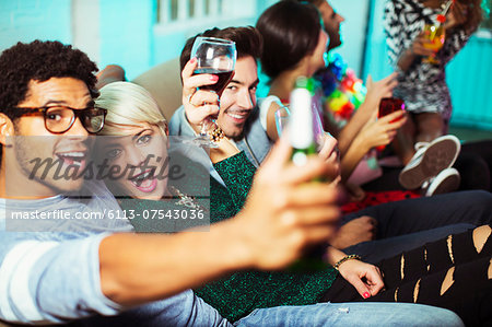 Friends drinking on sofa at party