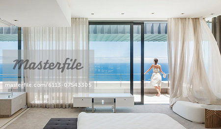 Woman on modern balcony overlooking ocean