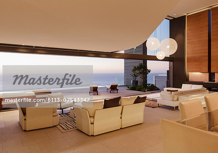 Living room in modern house overlooking ocean at sunset