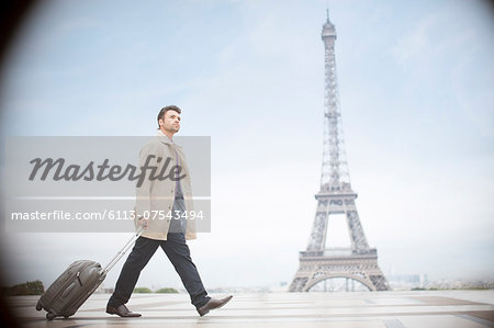 Businessman pulling suitcase near Eiffel Tower, Paris, France