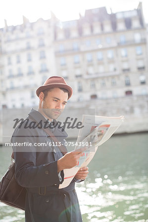 Businessman reading newspaper along Seine River, Paris, France