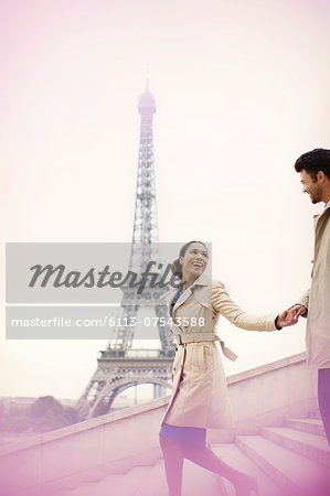 Couple descending stairs by Eiffel Tower, Paris, France