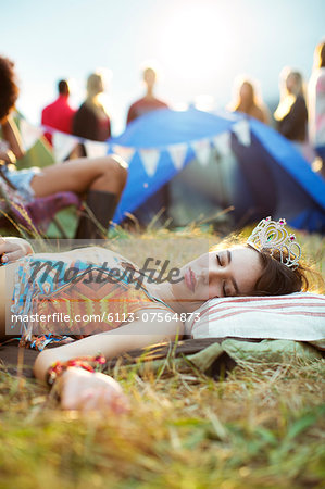 Woman in tiara sleeping outside tent at music festival