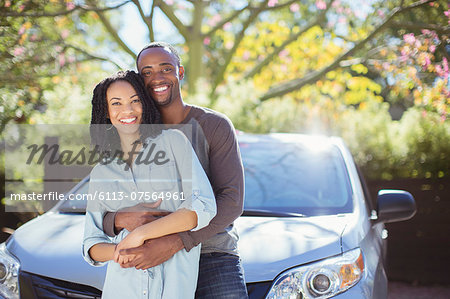 Portrait of happy couple hugging outside car