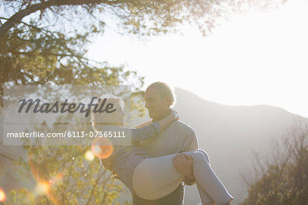 Senior man carrying woman outdoors