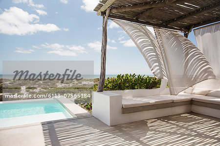 Curtains blowing in wind on luxury poolside patio overlooking ocean