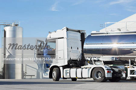 Truck driver climbing into stainless steel milk tanker