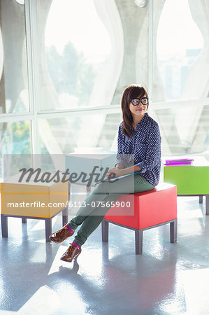 Creative businesswoman waiting on colorful stool