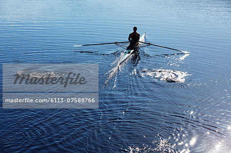 Man rowing scull on lake