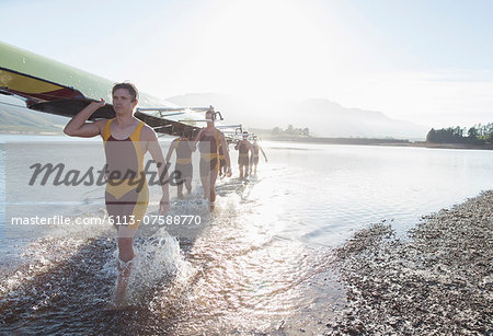 Rowing crew carrying scull out of lake