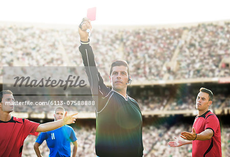 Referee flashing red card in soccer game Referee flashing red card in soccer game