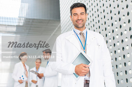 Portrait of confident doctor holding digital tablet in hospital corridor Portrait of confident doctor holding digital tablet in hospital corridor
