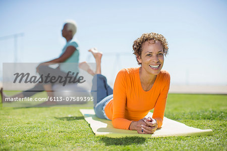 Portrait of smiling woman on yoga mat in park