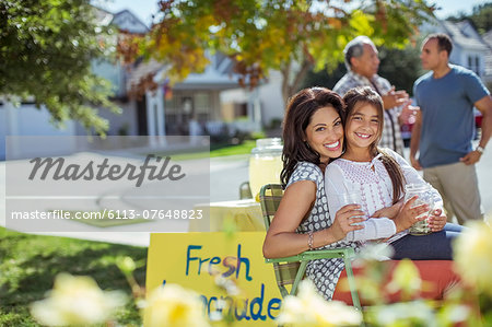 Portrait of mother and daughter hugging at lemonade stand