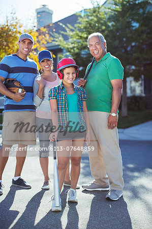 Portrait of happy multi-generation family playing baseball in street