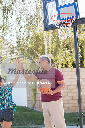 Grandfather and granddaughter high fiving at basketball hoop