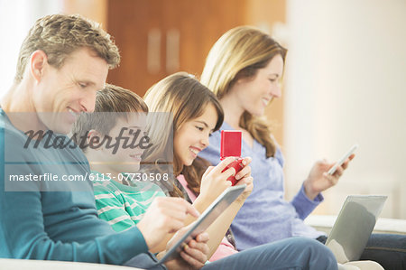 Family using technology on sofa Family using technology on sofa