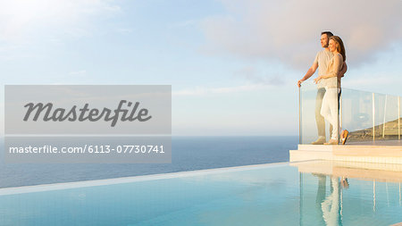 Couple overlooking ocean from modern balcony Couple overlooking ocean from modern balcony
