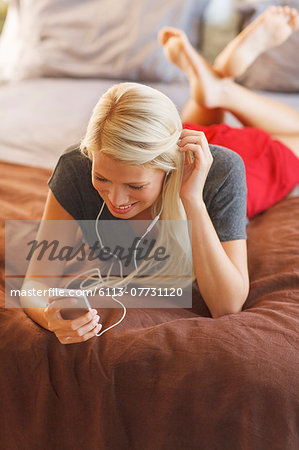 Woman listening to mp3 player on bed