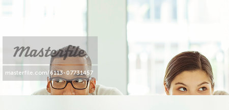 People peeking over cubicle in office