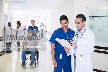 Doctor and nurse reading medical chart in hospital hallway