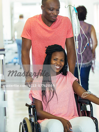 Man wheeling girlfriend in hospital hallway