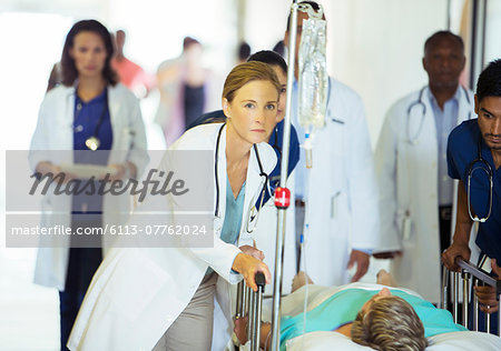 Doctors and nurses wheeling patient in hospital hallway