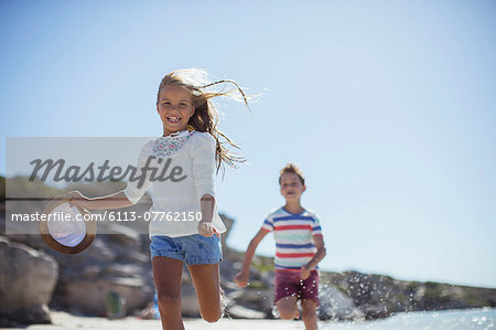 Young girl and boy running along beach