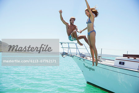 Couple jumping off boat together Couple jumping off boat together