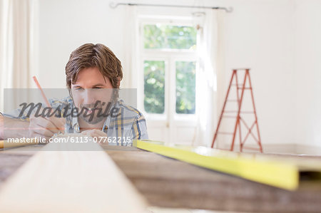 Man marking wood in living area