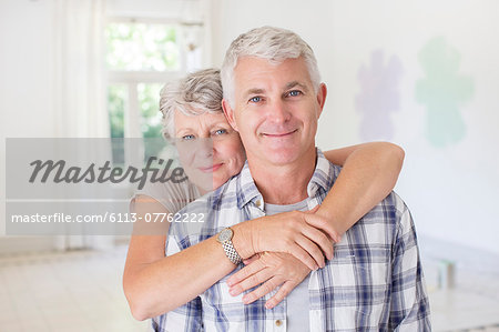 Older couple hugging in living space Older couple hugging in living space
