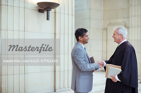 Judge and lawyer shaking hands in courthouse