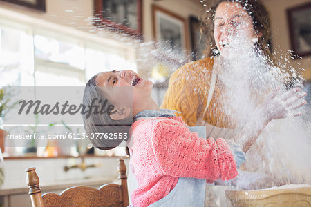 Mother and daughter playing with flour in the kitchen