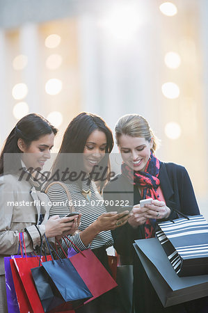 Women using cell phones on city street