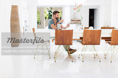 Man using digital tablet at breakfast table in modern dining room