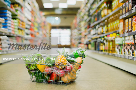 Close up of full shopping basket on floor of grocery store