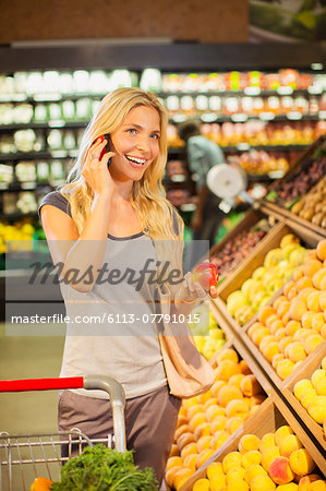 Woman talking on cell phone and shopping in grocery store