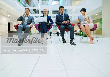 Business people sat in chairs working in office building Business people sat in chairs working in office building