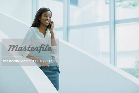 Businesswoman talking on cell phone on office building stairs