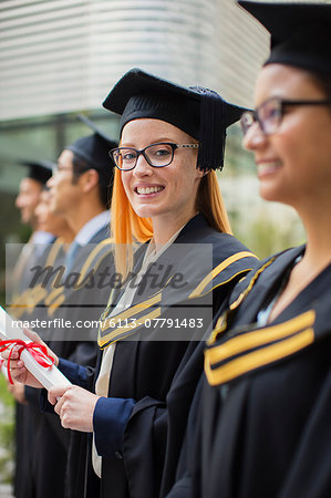 Woman in cap and gown standing with colleges